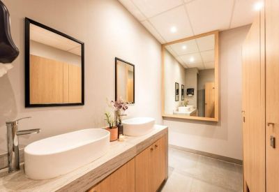 Modern restroom featuring white vessel sinks and wood cabinetry.
