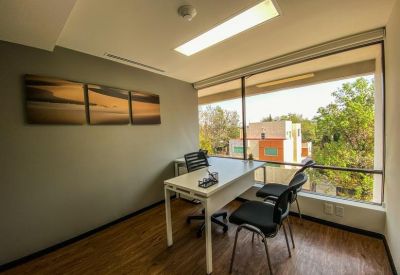 Private internal office suite with a white desk and a large window providing natural light.