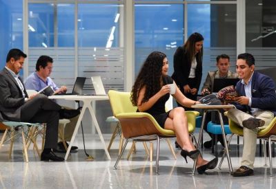 Professionals collaborating in a bright communal lounge with yellow armchairs.