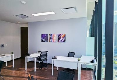 Bright multi-desk office space with large windows overlooking the city.