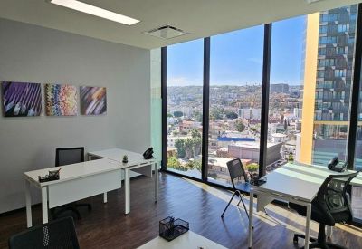 Spacious office suite with corner windows and three art prints on the wall.