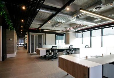 Modern workspace with white desks and black chairs under industrial-style ceilings.