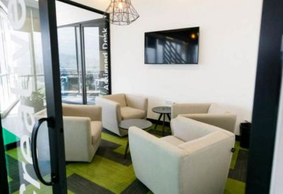 Informal meeting space with cream-colored armchairs and a wall-mounted TV.