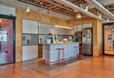 Modern kitchen and breakout area with a tiled island, red stools, and wood-paneled walls.