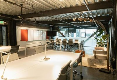 Industrial-style workspace with large white desks and exposed ceiling beams.