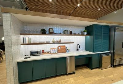 Sleek modern kitchen area with teal cabinets, white tile backsplash, and wooden accents.