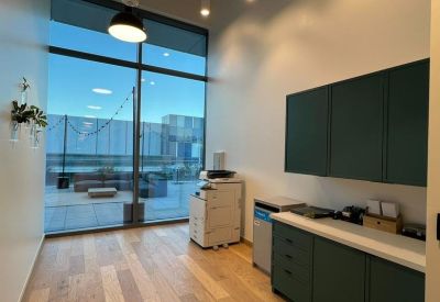 Bright office printing station with teal cabinetry and floor-to-ceiling windows.