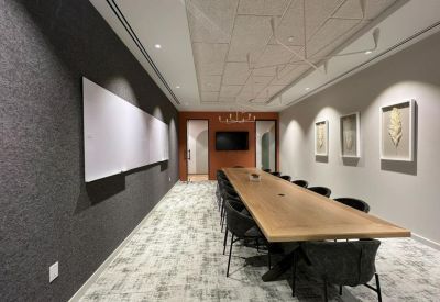 Spacious boardroom featuring a long wooden table and gray textured accent wall.