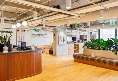 Reception area with a warm wood desk, indoor plants, and soft hanging pendant lights.