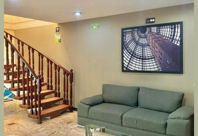 Communal lounge area with a green sofa, glass coffee table, and decorative wall art.