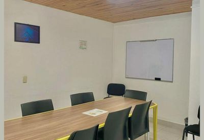 Meeting room with a long wood-topped table and white board under a wood-paneled ceiling.