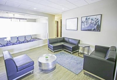 Lounge area with black leather sofas, metal coffee table, and views into a meeting room.