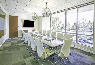 Large boardroom with a sleek table, white executive chairs, and expansive windows.