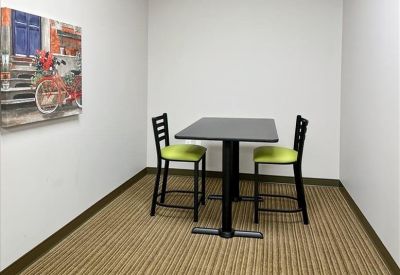 Breakout area featuring a black bistro table, lime green chairs, and colorful wall art.