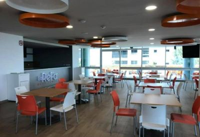 Spacious dining area with orange and white chairs and large windows.