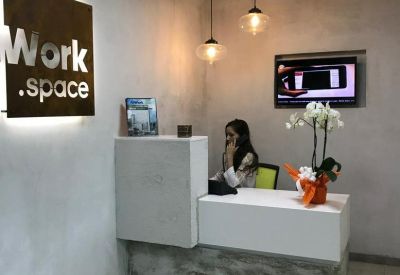 Modern reception desk with a branded wall sign and warm pendant lighting.