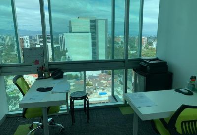 Bright corner office space with two white desks and expansive city views.
