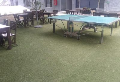 Outdoor communal terrace with artificial turf, dining tables, and a ping pong table.