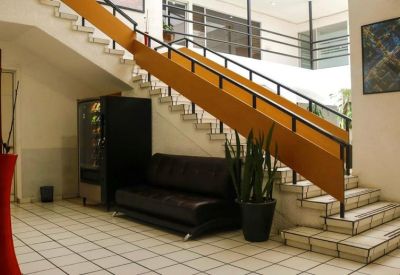 Building lobby with a modern staircase, black leather sofa, and a yellow feature wall.