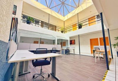Bright coworking area with workstations under a large geometric glass skylight.