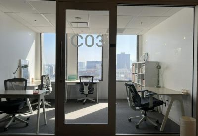 Bright three-person private office with glass walls and views of the city skyline.