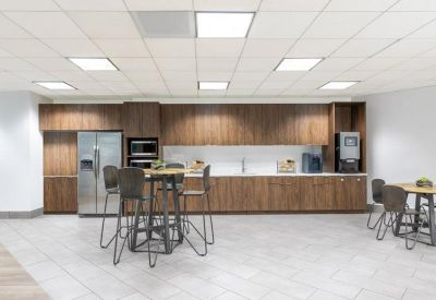 Bright office kitchen featuring dark wood cabinetry, stainless steel appliances, and high-top seating.