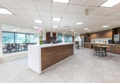 Modern reception area with a wooden front desk and adjacent kitchen breakroom.
