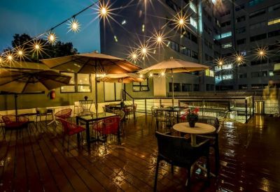 Nighttime rooftop terrace with patio seating and string lights.