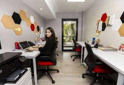 Shared office space with white desks and black ergonomic chairs.