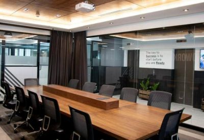 Spacious boardroom featuring a long wooden table, black mesh chairs, and glass walls.
