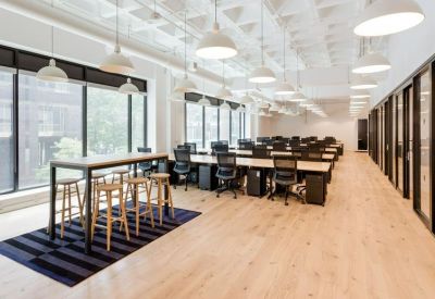 Open-plan office with rows of workstations and a high-top collaboration table.