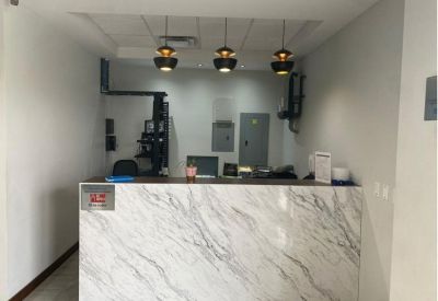 Reception area featuring a marble-patterned front desk and three modern pendant lights.