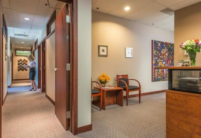 Office hallway leading past a reception desk with a floral arrangement.