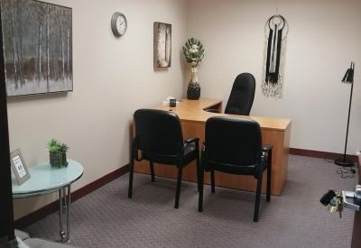 Private office featuring a wooden L-shaped desk and framed tree artwork.