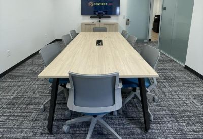 Boardroom with a long light-wood table and integrated AV technology.