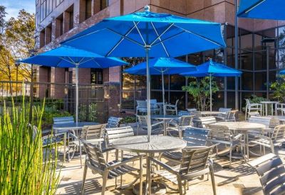 Outdoor patio area with blue umbrellas and silver tables for communal dining.