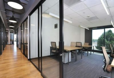Modern glass-walled office suite with wooden floors and bright lighting.