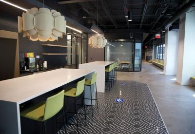 Kitchen breakroom area with white islands, green bar stools, and modern light fixtures.