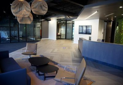 Spacious reception lobby with a large blue desk, lounge seating, and designer pendant lights.