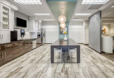 Modern communal kitchen and breakout area with a long high-top table and pendant lighting.