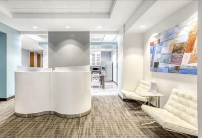 Clean white reception lobby with curved front desk, white lounge chairs, and vibrant wall art.