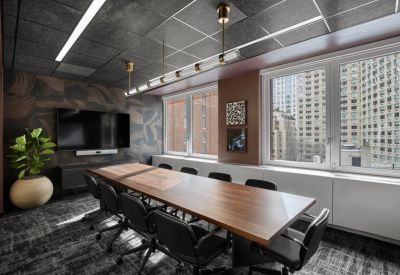 Modern conference room featuring a long wooden table, black chairs, and large windows with city views.