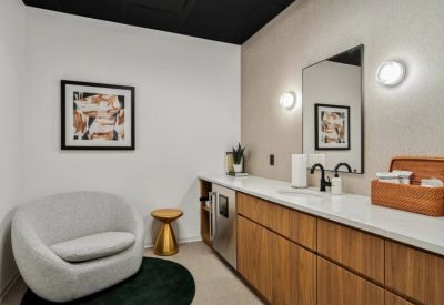 Wellness room with a comfortable grey armchair, wooden cabinetry, and a sink area.