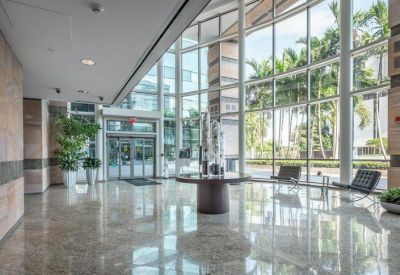 Expansive glass-walled lobby with high ceilings and natural light reflecting on marble floors.