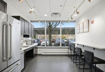 Staff breakroom with dark cabinetry, stainless steel fridge, and a window-side breakfast bar.