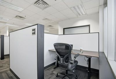 Individual workstation in an open-plan office with a grey ergonomic chair and privacy screen.