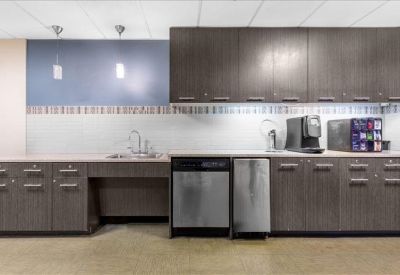 Modern communal kitchen area with dark wood cabinetry and integrated appliances.
