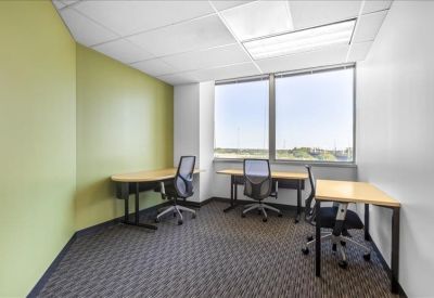 Private three-person office suite with green feature wall and large window.