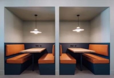 Pair of modern semi-private meeting booths with orange cushioned seating.