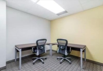Two-person workspace with minimalist wooden desks and grey mesh chairs.